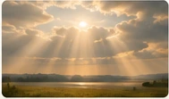 Sunlight breaking through clouds over a landscape